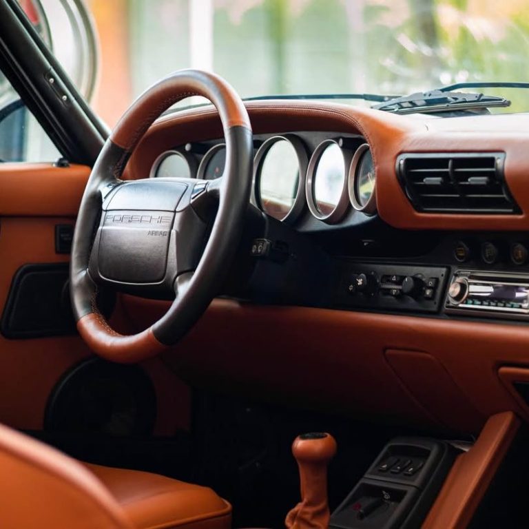 Innenansicht eines Autos mit braunem Interieur und einem klassischen Lenkrad.